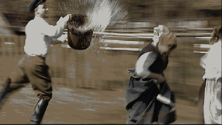 Mężczyzna biegnie z wiadrem wody za kobietami